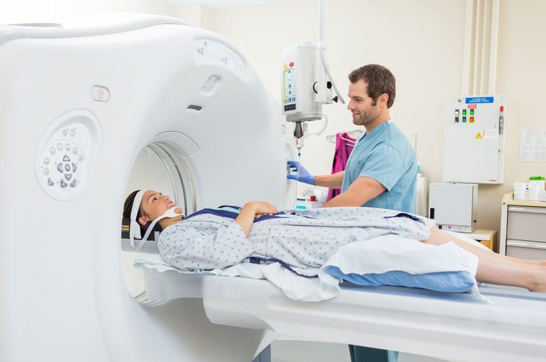 Woman undergoing MRI scan assisted by a radiologist